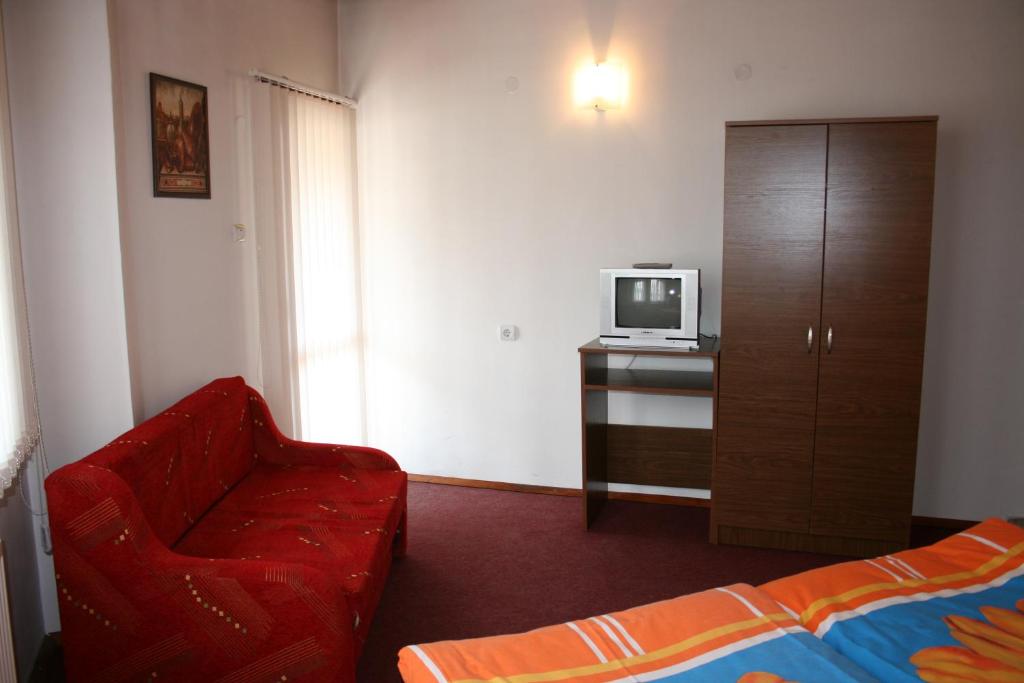 バンスコにあるAseva House Family Hotelのリビングルーム(赤い椅子、テレビ付)