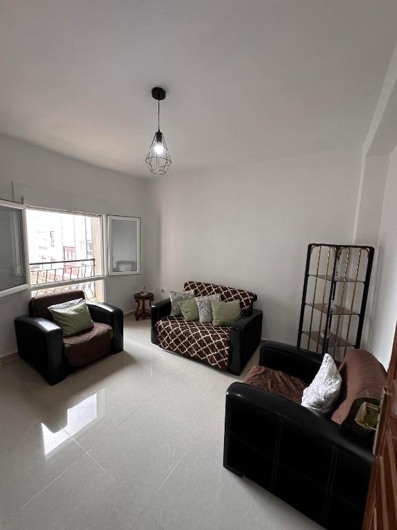 スキクダにあるAppartement F3 Bouzaaroura Skikdaのリビングルーム(黒いソファ2台付)