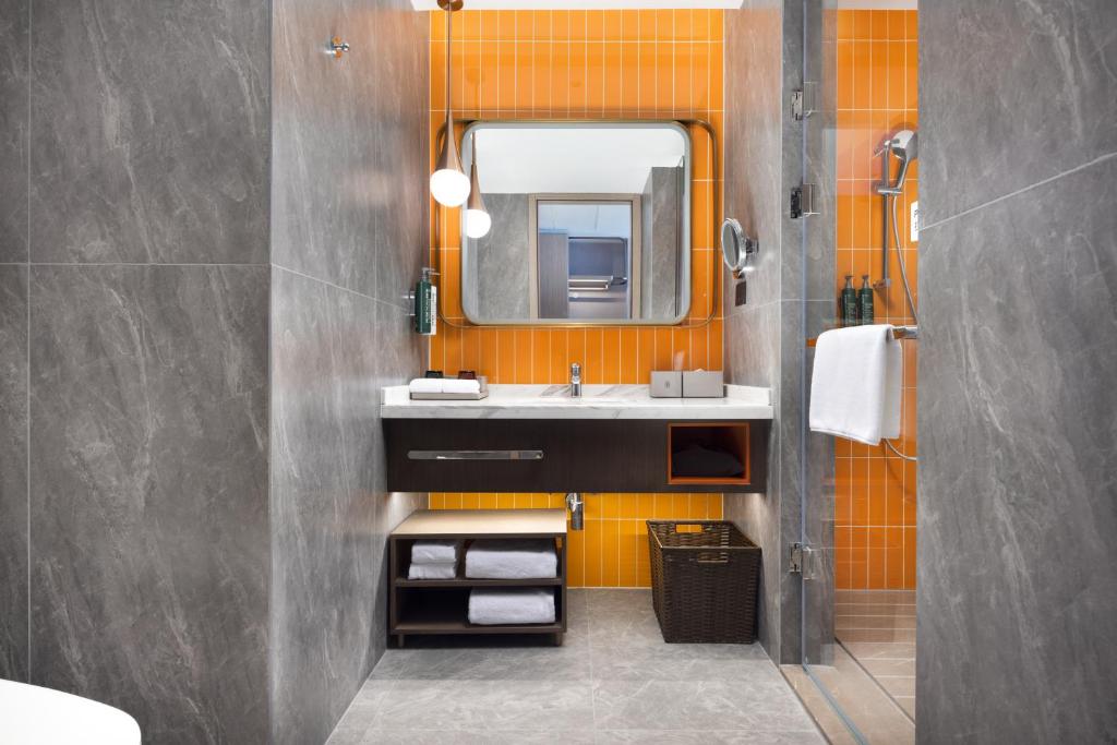 an orange bathroom with a sink and a mirror at Home2 Suite by Hilton Wuhan Economic Development Zone in Wuhan