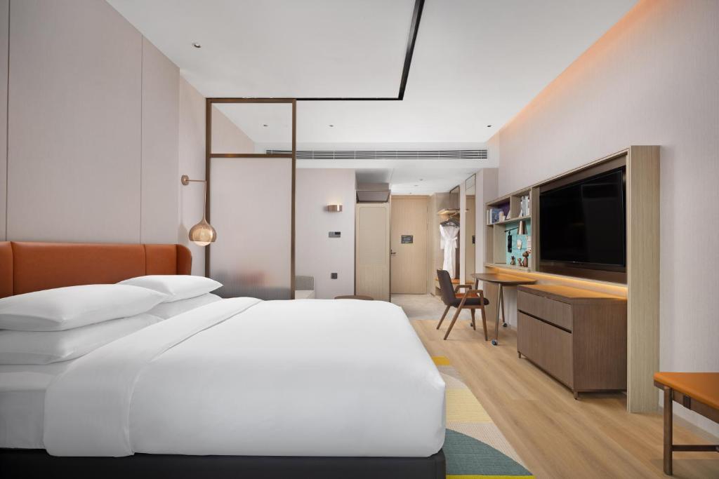 a bedroom with a large white bed and a desk at Home2 Suite by Hilton Wuhan Economic Development Zone in Wuhan