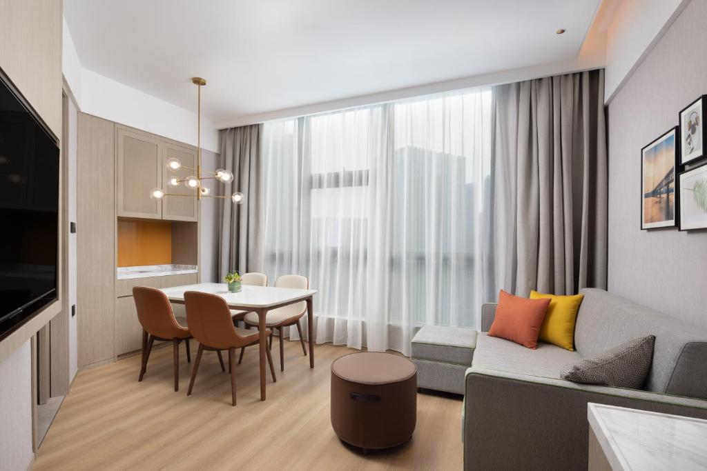 a living room with a couch and a table and chairs at Home2 Suite by Hilton Wuhan Economic Development Zone in Wuhan