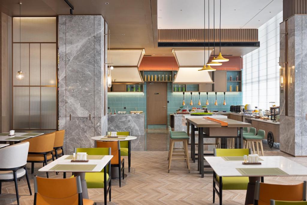 a restaurant with tables and chairs and a kitchen at Home2 Suite by Hilton Wuhan Economic Development Zone in Wuhan