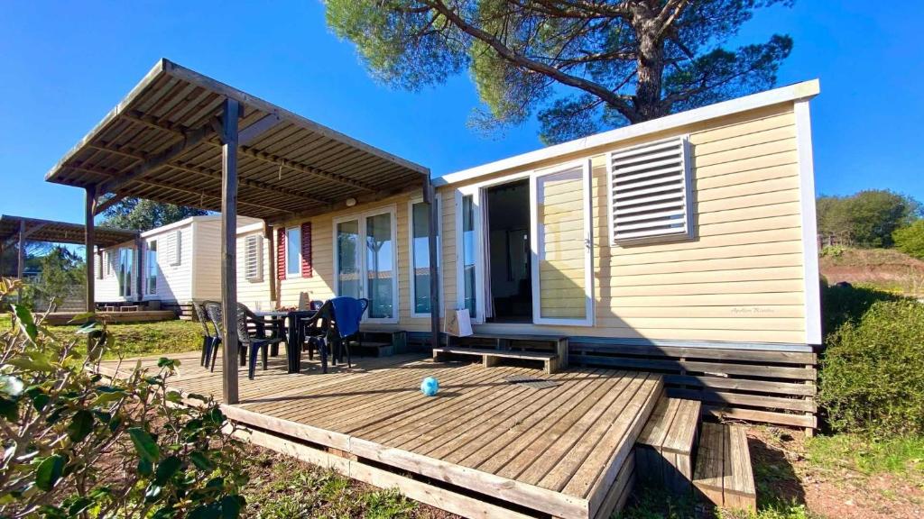 Cette petite maison dispose d'une terrasse en bois avec une table. dans l'établissement Camping 5 étoiles - Parc aquatique - eebaff, au Muy