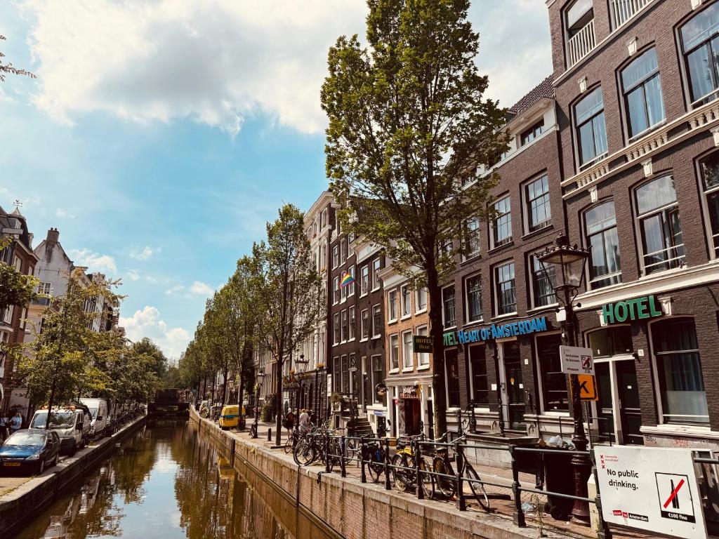 a canal in a city with buildings and a river at Heart of Amsterdam Hostel in Amsterdam