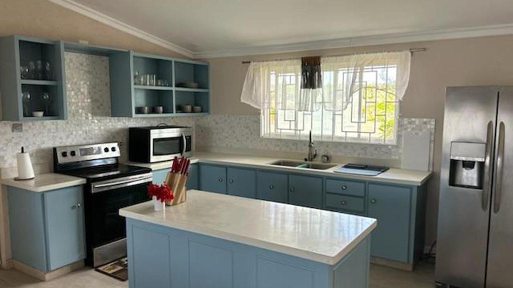 a kitchen with blue cabinets and a stove and refrigerator at Welcome to Hope Winds, a charming property ranch-style house on a seren in Christ Church