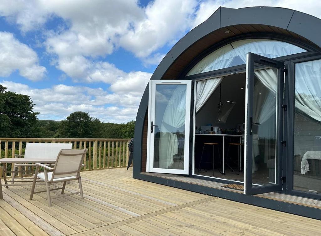 a glass house with a table and a chair on a deck at Byrnside Lodge in Latheron