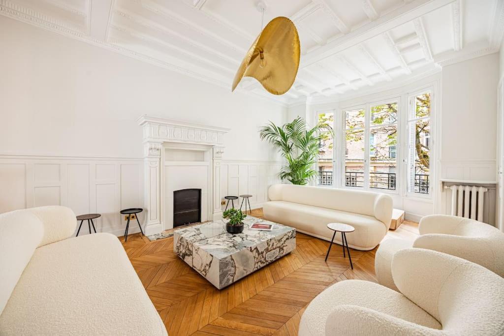 Elle comprend un salon doté d'un mobilier blanc et d'une cheminée. dans l'établissement Amazing Apartment # 5Bedrooms #Paris 16 #Trocadero, à Paris