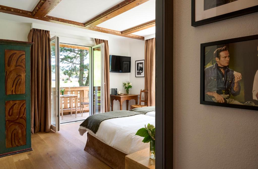 a bedroom with a bed and a view of a patio at Maison d'h&ocirc;tes Ermitage in Chateau-d'Oex