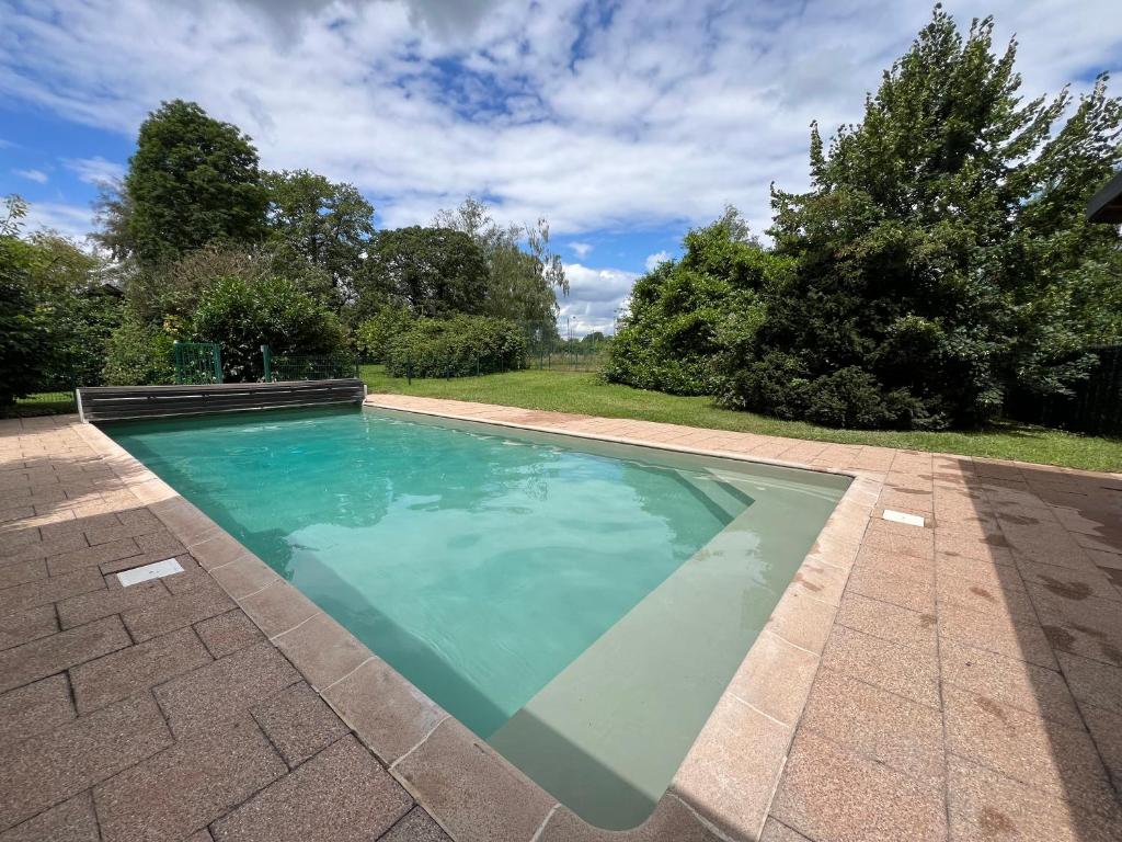 une piscine avec de l'eau bleue dans une cour dans l'établissement Charmante Demeure Piscine au Calme Parc Tennis, à La Walck