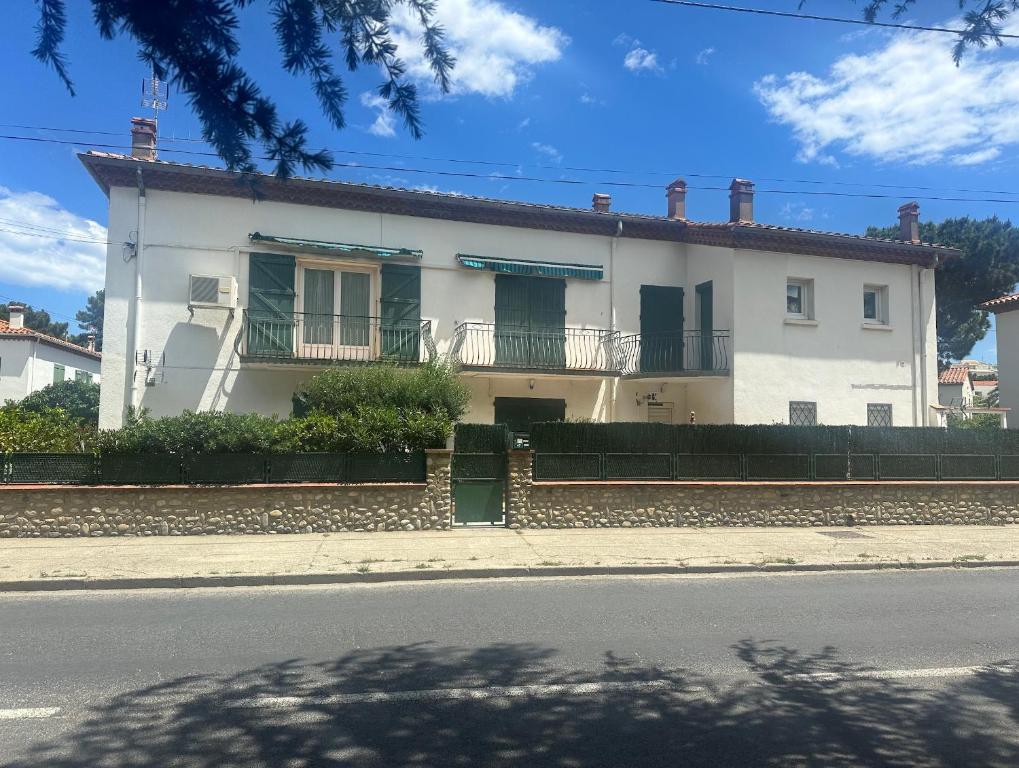 Maison blanche avec volets verts dans une rue dans l'établissement Can Roger, à Argelès-sur-Mer