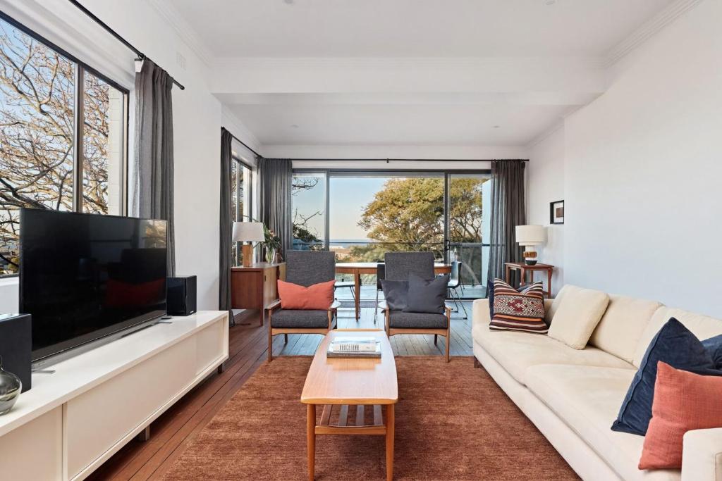 a living room with a white couch and a large tv at Coogee Treetops in Sydney