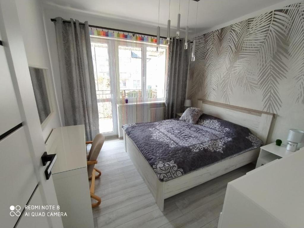 a bedroom with a bed and a large window at Willa Loka Apartamenty in Władysławowo