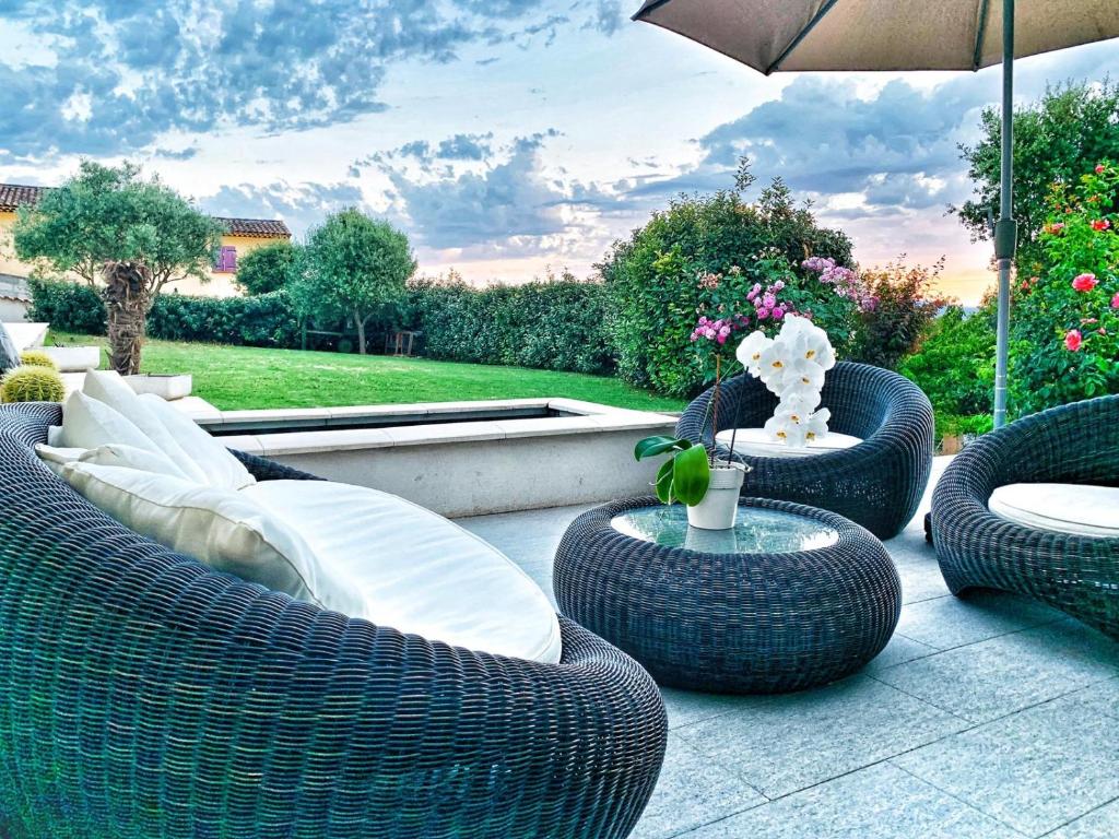une terrasse avec des chaises et des tables en osier et un parasol dans l'établissement Séjour au soleil avec piscine, à Vinon-sur-Verdon