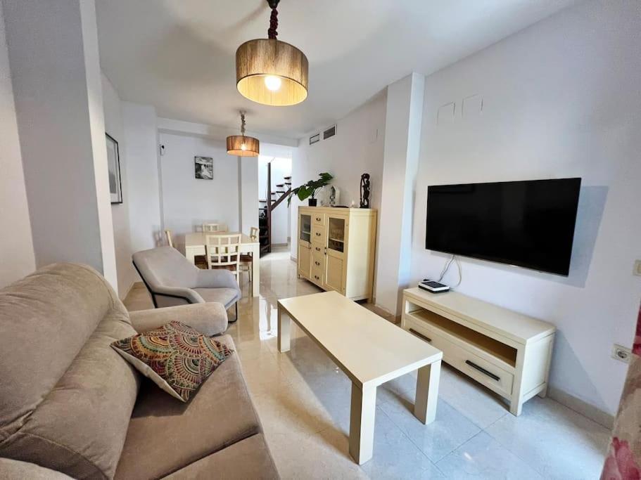 Una sala de estar con un sofá y un televisor de pantalla plana. en Nuevo y exclusivo ático de playa, en Fuengirola