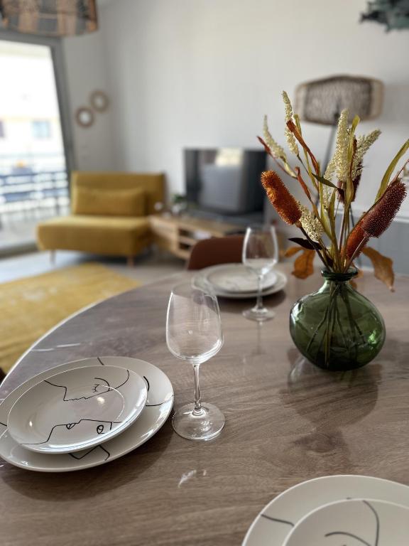 une table avec des assiettes et des verres et un vase avec des fleurs dans l'établissement L'échappée, à Bandol
