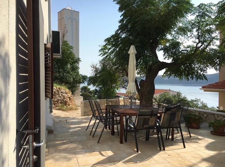 einen Tisch und Stühle mit einem Regenschirm und einem Baum in der Unterkunft Holiday Home Jan in Stara Novalja