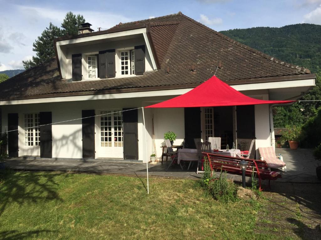 une maison avec une tente rouge devant elle dans l'établissement Maison Le Boubioz, à Ugine