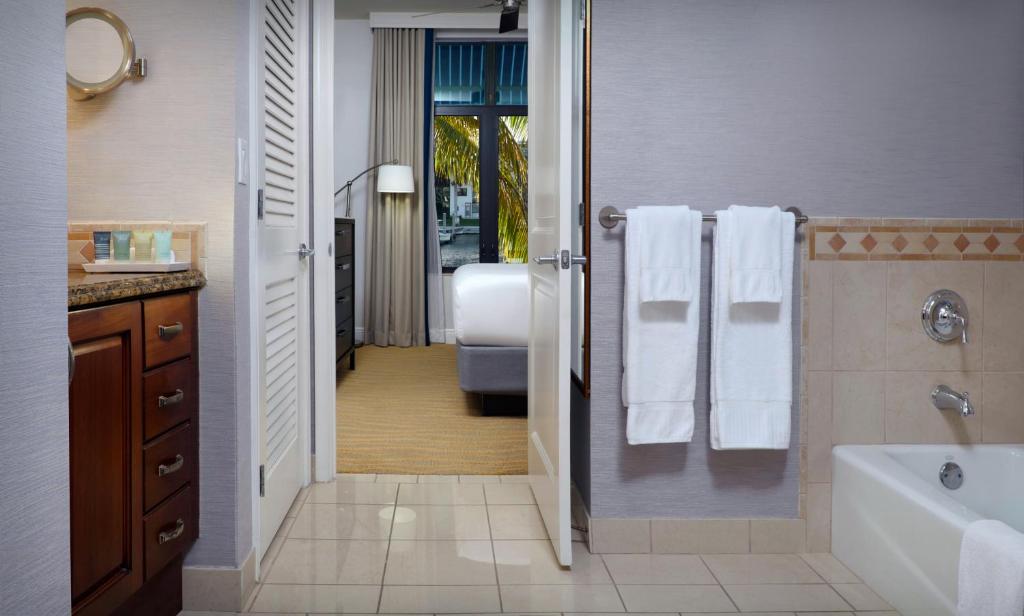a bathroom with a tub and a shower with towels at Naples Bay Resort and Marina in Naples