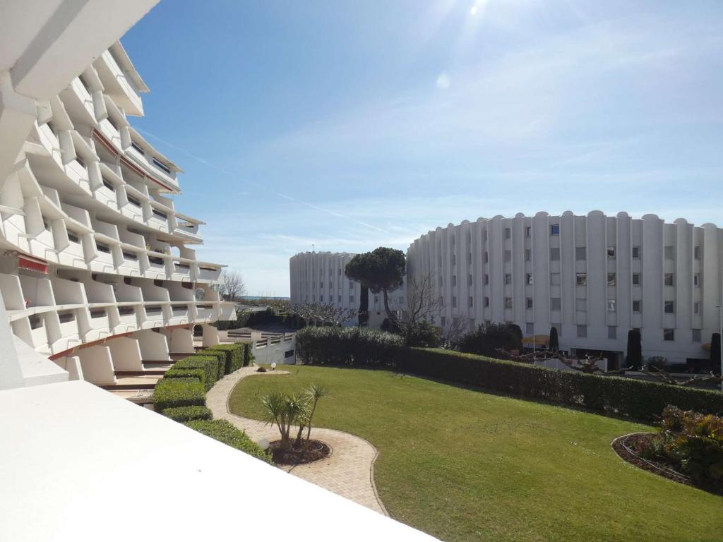 - une vue extérieure sur un bâtiment avec une pelouse dans l'établissement Studio Cabine - Loggia Sud - Proche Plage et Commerces - 4 Pers - Parking Privé - FR-1-328-104, à La Grande Motte