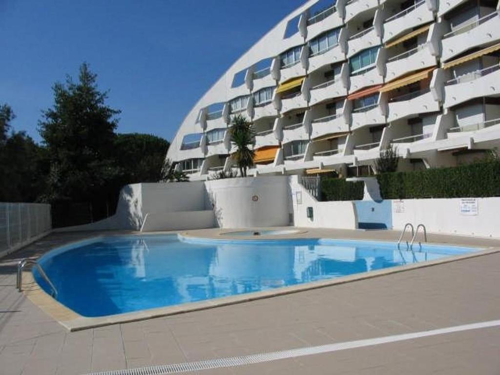 une grande piscine devant un immeuble dans l'établissement Studio Cabine Moderne avec Piscine, Proche Plage, Calme, Vert, Tout Confort - La Grande Motte - FR-1-328-105, à La Grande Motte