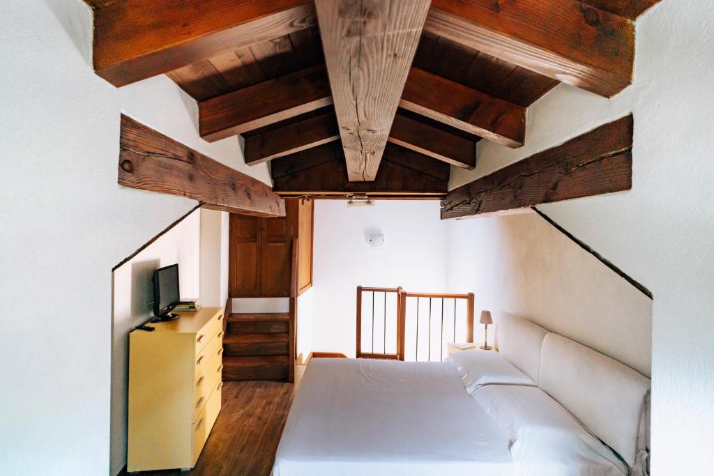 Saint MarcelにあるAosta Holiday Apartments - La Plantazの白いベッドと木製の天井が備わるベッドルーム1室が備わります。