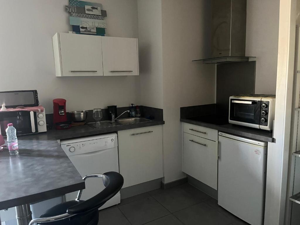une petite cuisine avec un évier et un micro-ondes dans l'établissement Chapelle, à Mimizan-Plage