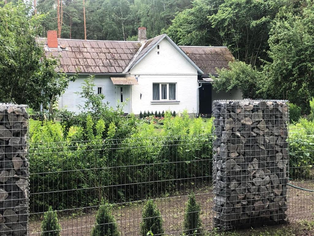 ein weißes Haus hinter einem Zaun im Garten in der Unterkunft Strawberry Forest in Jūrmala