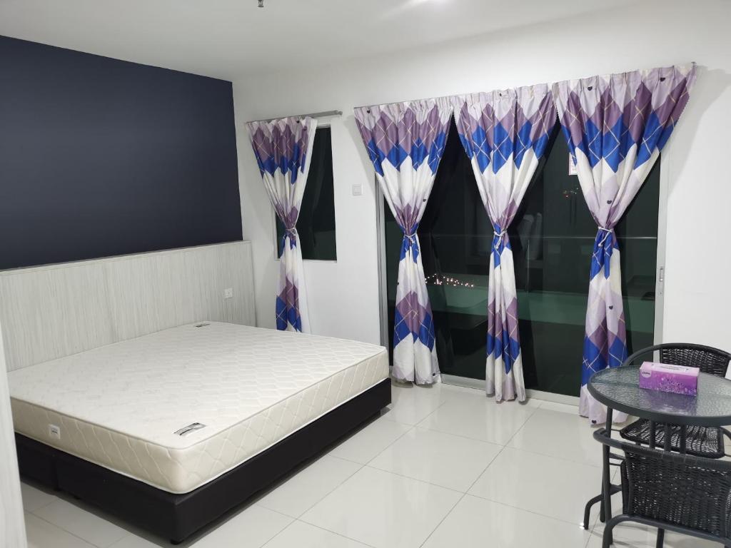 a bedroom with a bed and a table and curtains at Marina Island Couple Home Stay in Lumut