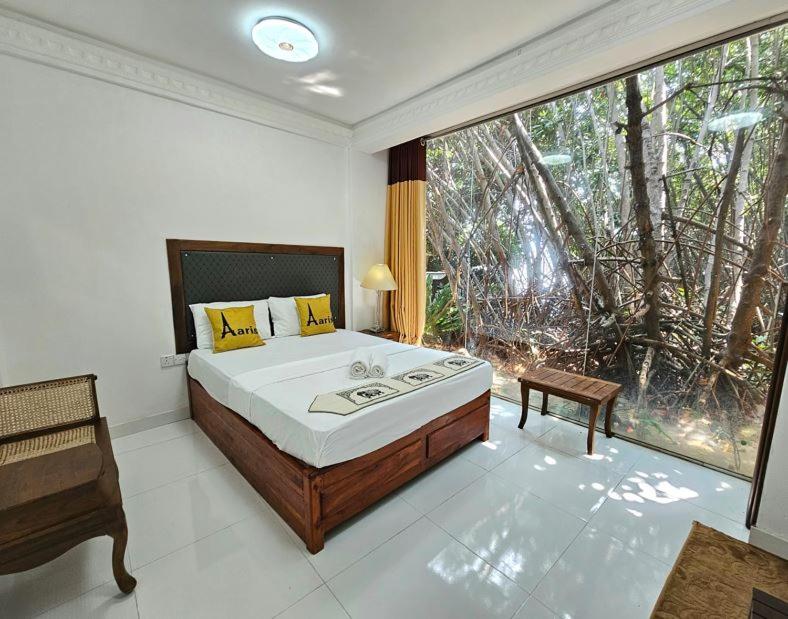 une chambre avec un grand lit et une grande fenêtre dans l'établissement Kadolana Heritage Kalpitiya, à Kalpitiya