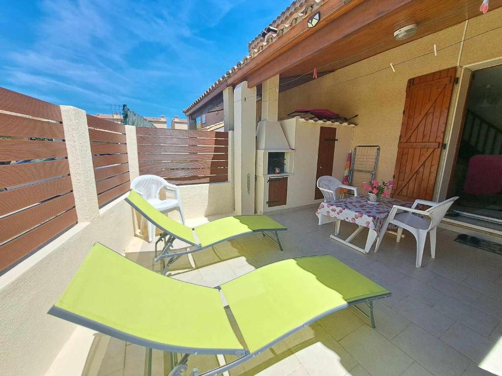 un patio avec des chaises et une table sur un balcon dans l'établissement Charmante maison 2 pièces cabine, terrasse, BBQ, parking privé, proche plage - Marseillan - FR-1-326-562, à Marseillan