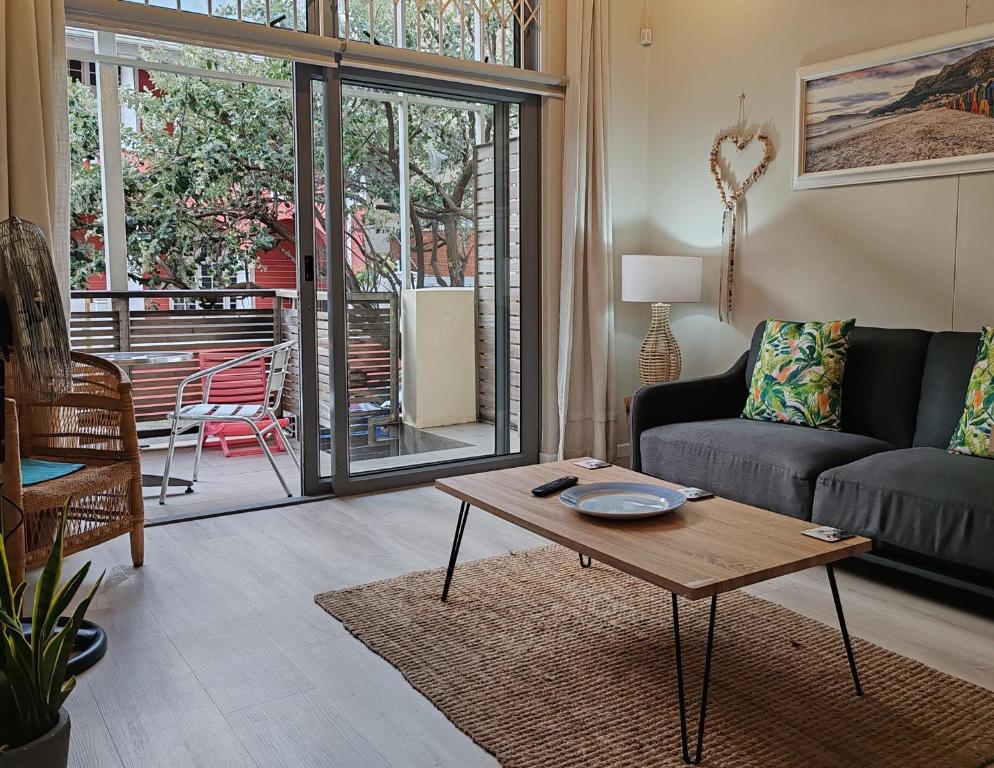 Una sala de estar con un sofá y una mesa de café. en Coastal Studio Empire Apartment, en Muizenberg