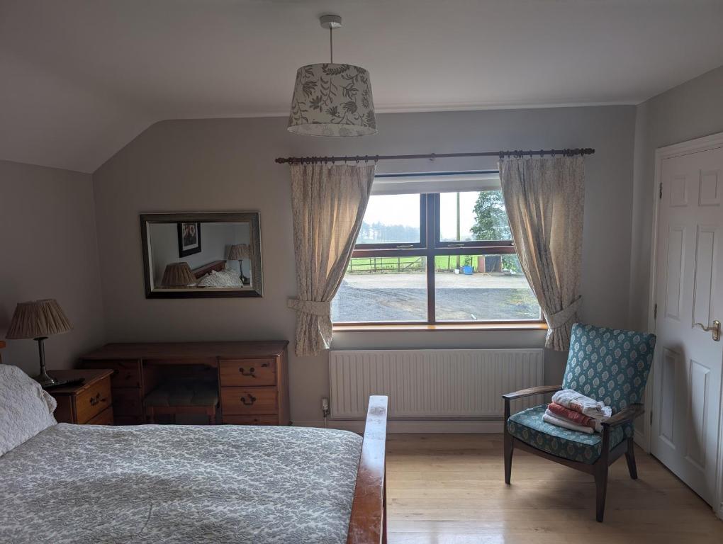 Un dormitorio con una cama y una silla y una ventana. en Clare House Bed & Breakfast, en Ballycastle