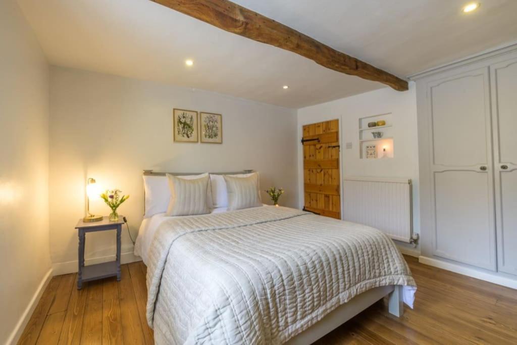 Schlafzimmer mit einem weißen Bett und Holzboden in der Unterkunft Bourton-on-the-Water Lovely 2Bed Cotswold Cottage in Bourton on the Water