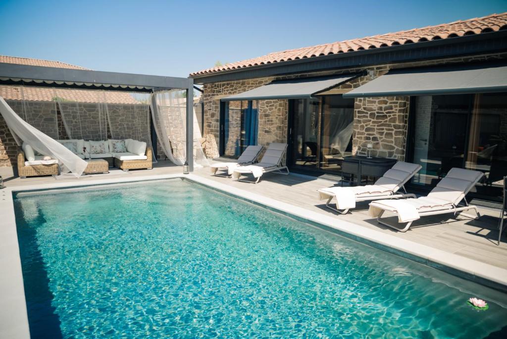 Una piscina con tumbonas y una casa. en Maison privée provençale, en Rochefort-du-Gard