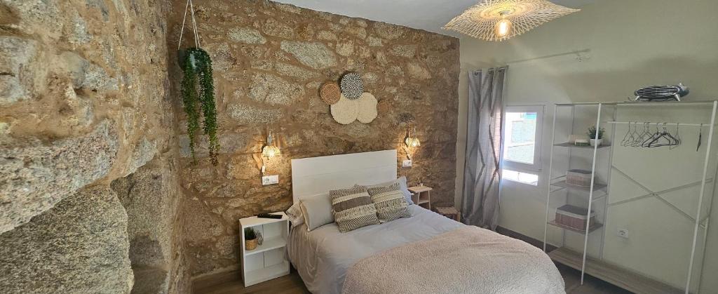 a bedroom with a stone wall with a bed at Casadeira de Mucha in Camariñas