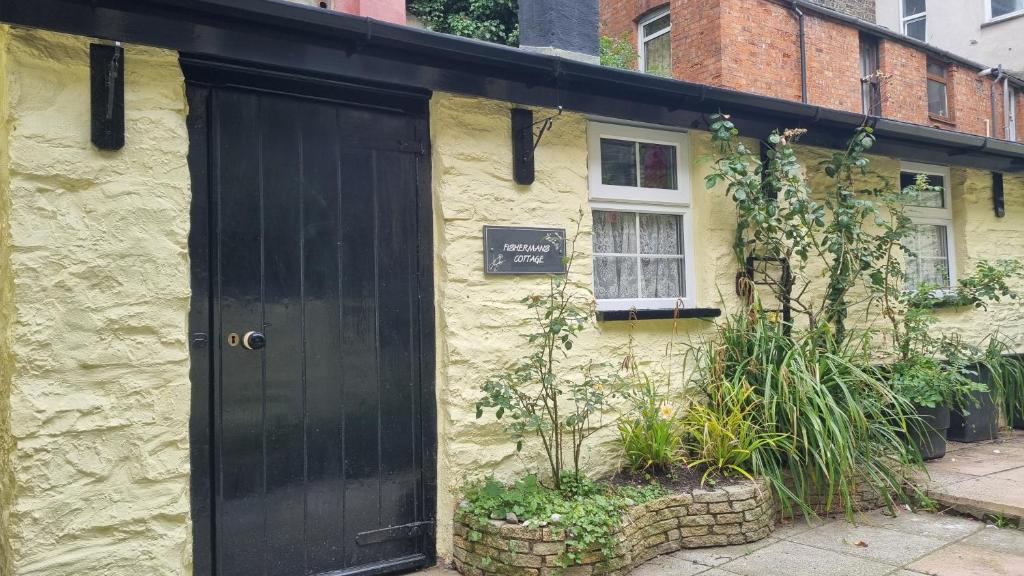 a black door on the side of a yellow building at Fisherman's Cottage in Aberystwyth