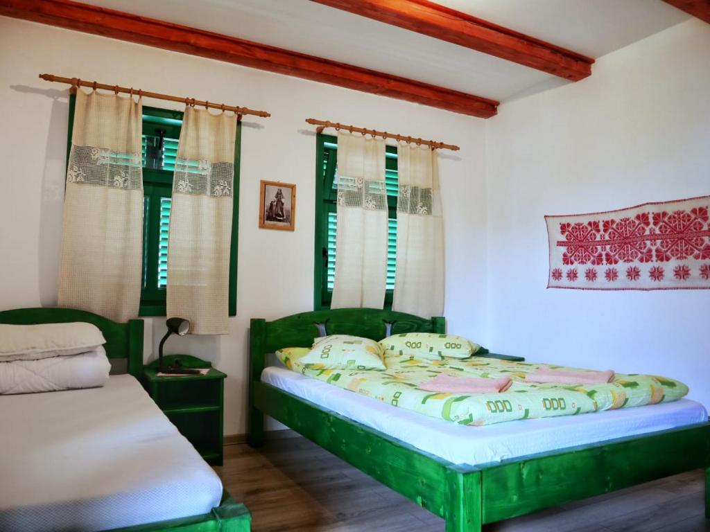 a bedroom with a green bed and windows at Panoráma Panzió Torockó in Rimetea