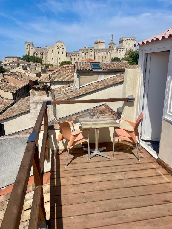 une terrasse en bois avec une table et des chaises sur un balcon dans l'établissement Le Toit D'Avignon - Intra-muros - Terrasse vue Palais des Papes - Idéal Festival - Climatisation - WiFi, à Avignon