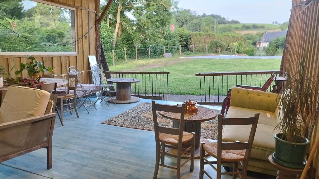 une terrasse avec des tables et des chaises ainsi qu'une grande fenêtre. dans l'établissement Chez Emma, à Léaupartie