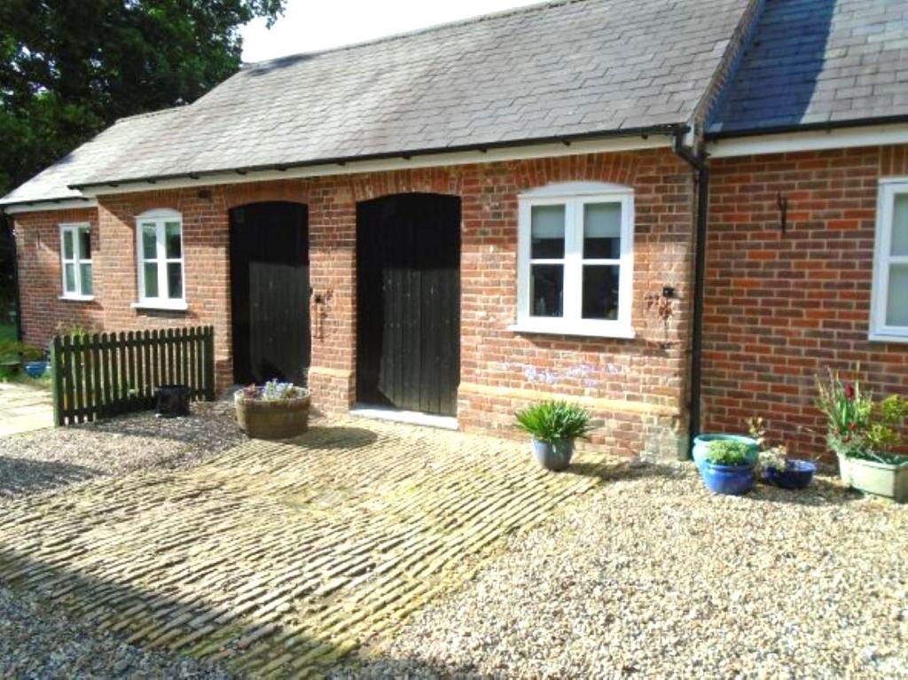 a red brick house with a courtyard in front of it at The Old Coach House in Bungay