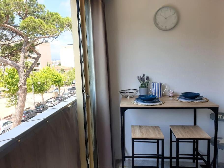 une table et deux tabourets sur un balcon avec une horloge dans l'établissement Palm Beach Escape, à Cannes