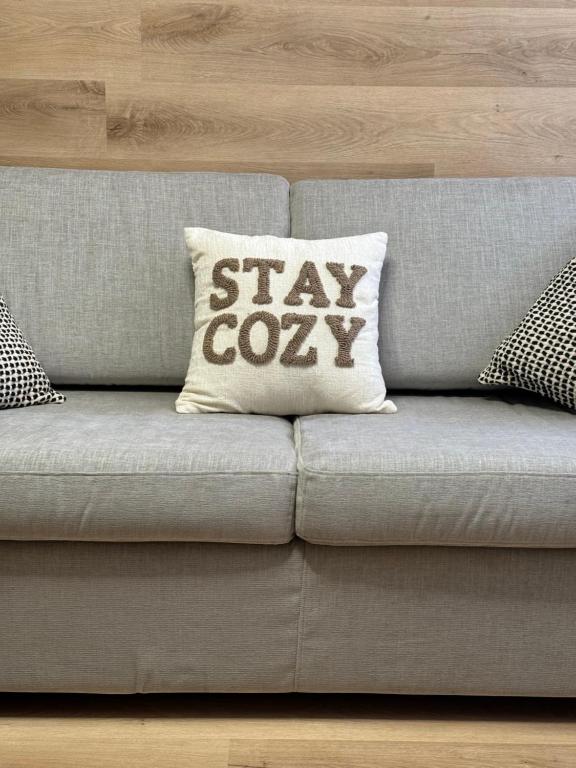 a gray couch with a pillow with the words stay cozy at CozySuite Pinzolo centro New boutique apartment in Pinzolo