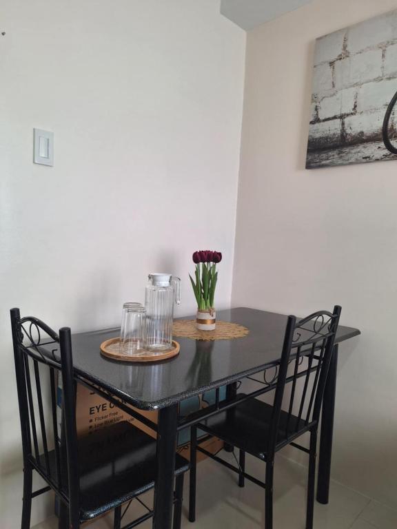 Una mesa negra con dos sillas y un jarrón de flores. en AJ Condominium, en Cebú