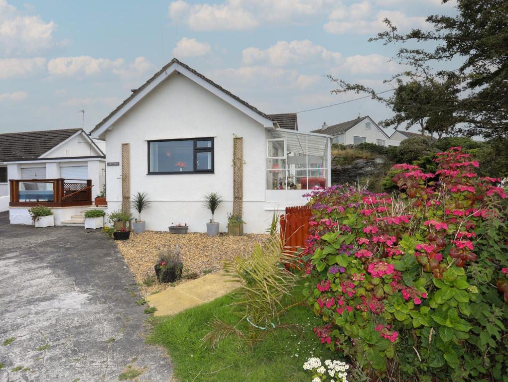 a white house with pink flowers in the yard at Greenfield in Holyhead