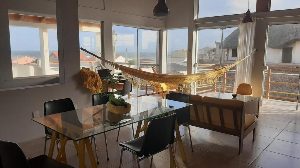 una sala da pranzo con un tavolo di vetro e un'amaca di Caracol · Sobrado Sissã: conforto, vista p o mar, 30km Chuí a Santa Vitória do Palmar