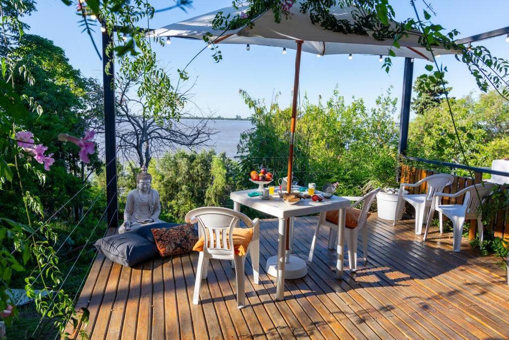 a deck with a table and chairs and an umbrella at Hermosa casa, terraza al río, Jacuzzi climatizado in Paraná