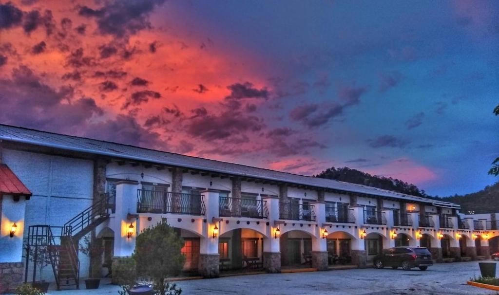 a building with a red sunset in the sky at Hotel Quinta Mision in Creel