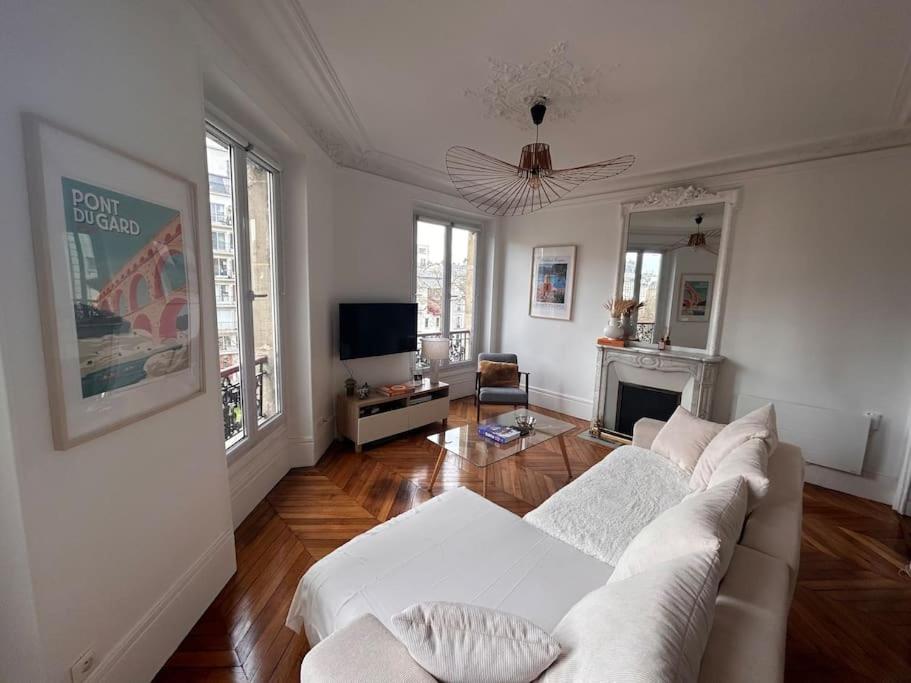 un salon avec un canapé blanc et une cheminée dans l'établissement Superbe appartement Paris 17ème 55m2, à Paris
