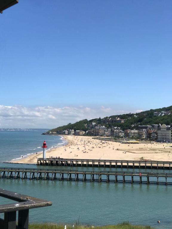 une plage avec une jetée et une plage avec un phare dans l'établissement HORIZON VUE MER parking gratuit, à Deauville