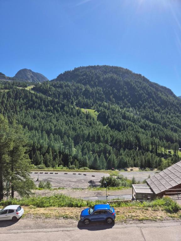 une voiture bleue garée devant une montagne dans l'établissement Neige et confort, à Isola 2000
